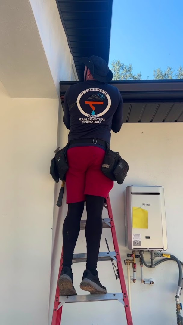 Installer on a ladder fitting gutters to a home, Central Florida